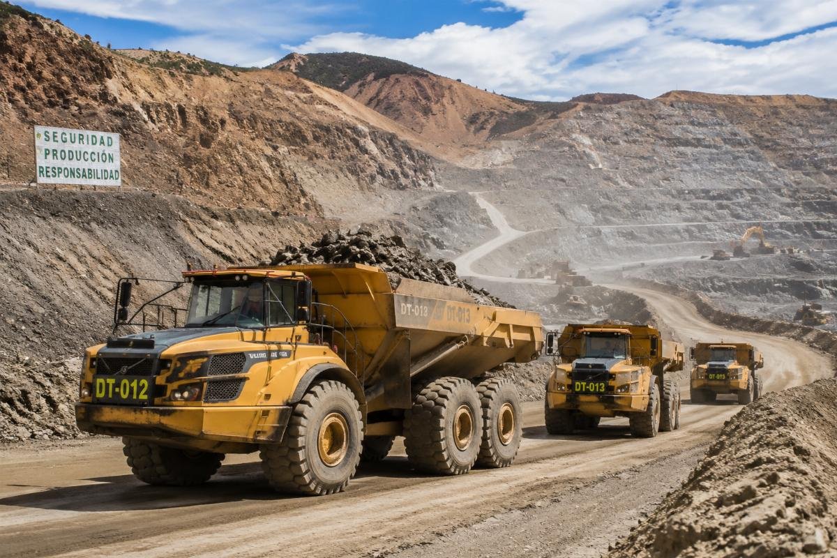 A fleet of articulated dump trucks operating at an open pit mining site in Latin America
