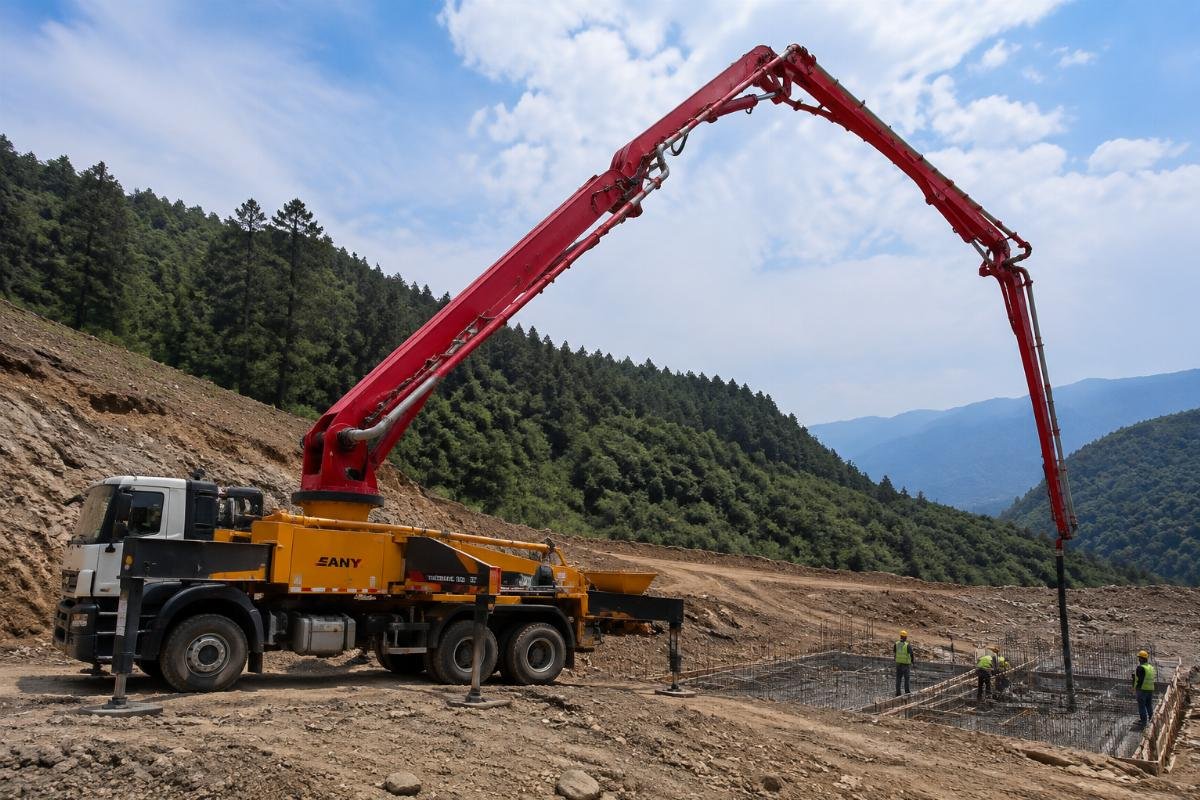 stationary concrete boom placer working on unpaved remote site Concrete boom placer operating on a remote construction site, with no paved access roads in view