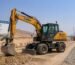 A 15-ton rubber tire wheel excavator operating on a desert road construction site